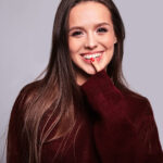 Smiling woman in a burgundy sweater with long brown hair, friendly and warm expression